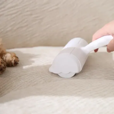 handheld-pet-fur-remover-ergonomic-design A close-up view of the back of the white pet hair remover being rolled across a sofa surface.