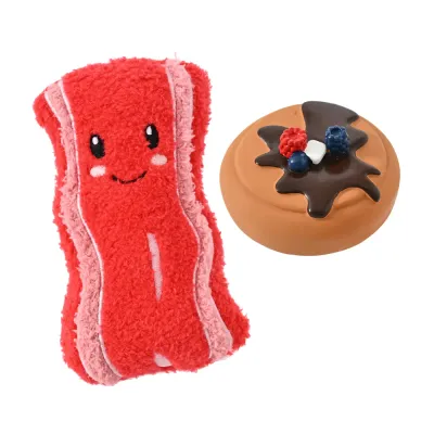 A 2-piece dog toy set featuring a red smiling plush bacon strip and a brown latex donut with berry toppings.