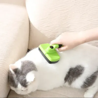 Professional Cat Deshedding Tool for Short and Long Hair Hand using a green self-cleaning slicker brush on a white and grey shorthair cat.