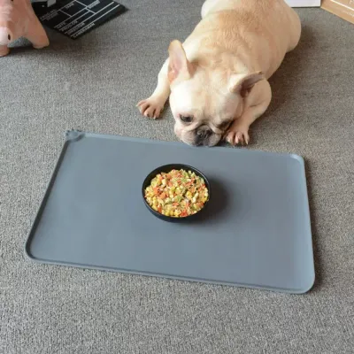 french-bulldog-with-food-bowl-on-silicone-mat A French Bulldog puppy lying down next to a black food bowl placed on a large grey silicone protective feeding mat.