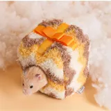 A hamster entering a yellow gift-box style plush nest on a soft white cloud-like background.