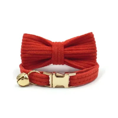 Front view of a red corduroy cat collar with a large bow tie, gold bell, and gold-plated breakaway buckle.