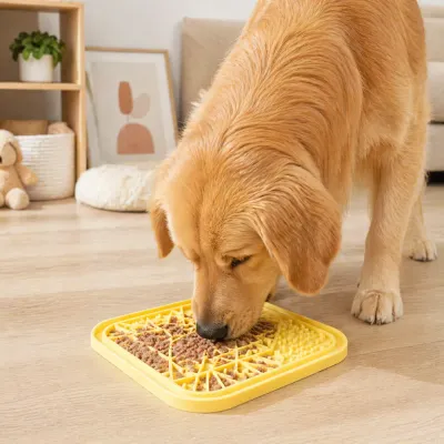 A dog enjoying wet food from a yellow silicone slow feeder mat on a wooden floor in a modern living room.