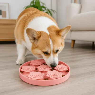 Corgi Using Pink Succulent Slow Feeder A Corgi dog focused on licking a pink rose-shaped silicone slow feeder mat on a wooden floor in a living room.