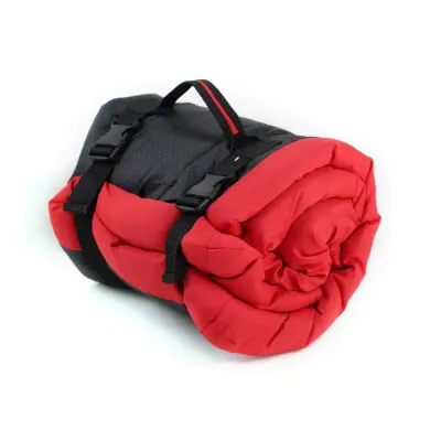 Red-Roll-Up-Pet-Travel-Mat Close-up of a red rolled-up dog travel mat with black adjustable buckles and a reinforced carry handle.