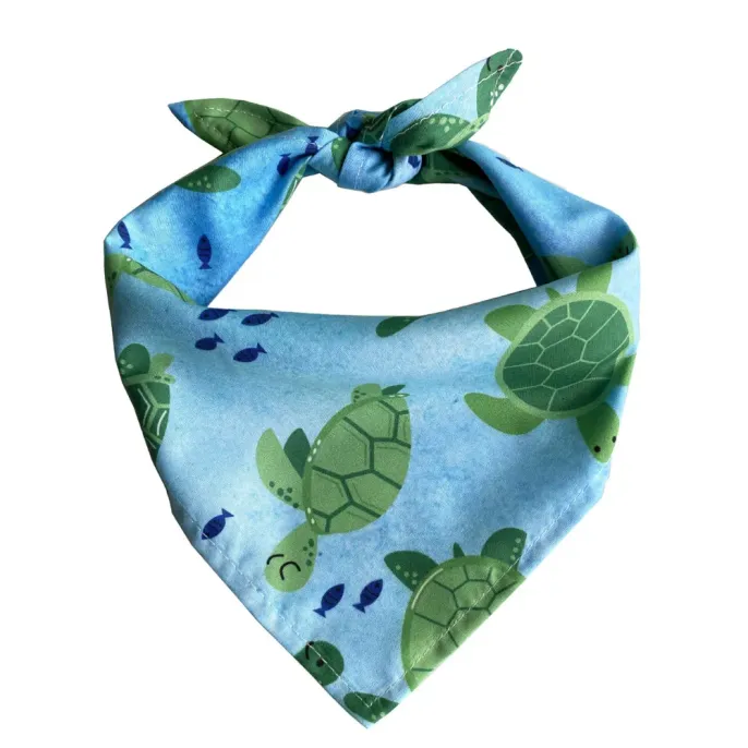 A blue dog bandana with green sea turtles and small dark blue fish illustrations.