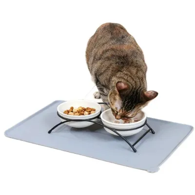 tabby-cat-eating-from-elevated-bowls-on-silicone-mat A tabby cat eating wet food from an elevated ceramic bowl set placed on a grey waterproof silicone pet feeding mat.