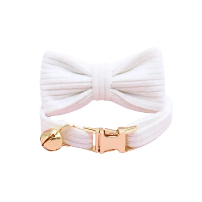 white-corduroy-cat-collar-safety-breakaway Studio shot of a white corduroy cat collar featuring a bow tie and a gold-colored safety release buckle.