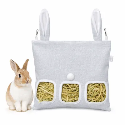 bunny-ear-hay-feeder-bag-grey A light grey rabbit hanging hay feeder bag with decorative bunny ears and a white pom-pom tail, shown next to a small brown and white rabbit.