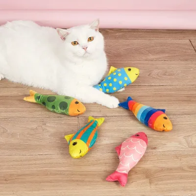 Indoor Cats Playing with Plush Catnip Fish Toys White indoor cat relaxing with colorful plush catnip fish toys on wooden floor