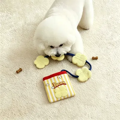 Small Dog Playing with Popcorn Plush Treat Toy Indoors Small white dog playing with plush popcorn crinkle treat pouch toy on soft indoor carpet