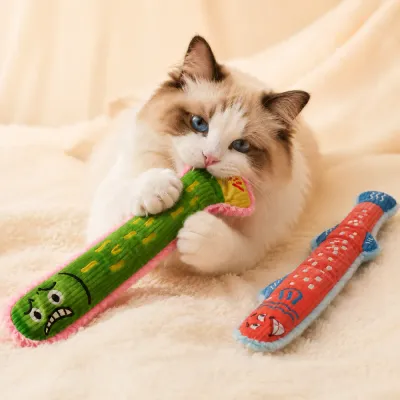 Fluffy indoor cat biting and hugging a long fish-shaped plush cat toy
