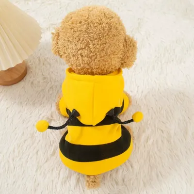 Small dog wearing a yellow fleece-lined bee hoodie on a soft indoor rug
