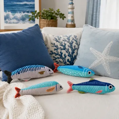 Four soft plush fish cat toys displayed on a coastal style sofa with blue and white ocean home decor.