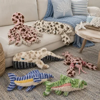 Ocean Plush Dog Toy Collection Display Ocean-themed plush dog toy collection displayed on a sofa, including lobster, octopus, whale, fish, crab, and alligator designs.