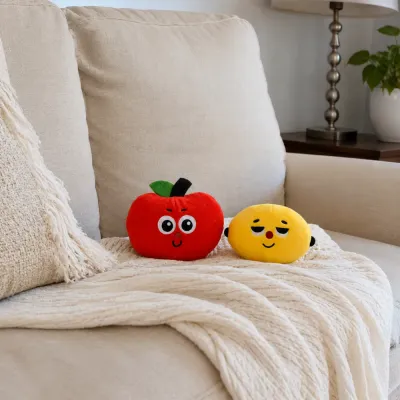 Fruit Plush Dog Toys on Living Room Sofa Red apple and yellow lemon plush dog toys displayed together on a beige living room sofa