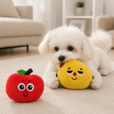 Small Dog Playing with Lemon Plush Toy Small white dog playing with a yellow lemon plush toy beside a red apple dog toy indoors