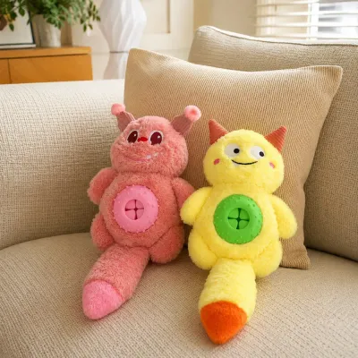 Pink and yellow monster plush treat dispensing dog toys displayed on a living room sofa