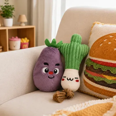 Eggplant and scallion plush dog toys displayed on a beige living room sofa beside a food-themed cushion