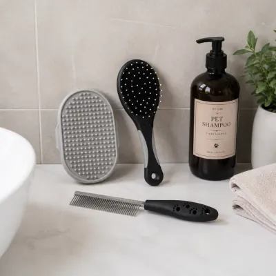 Pet Grooming Tools on Bathroom Counter Dog and cat grooming set with pin brush, silicone bathing glove and stainless steel comb beside pet shampoo.