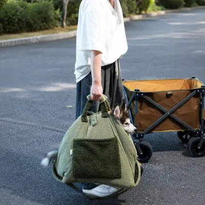 Portable Dog Carrier Bag for Outdoor Travel Person carrying a small dog in an olive green portable dog carrier bag during an outdoor trip