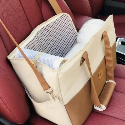 Brown and cream crossbody pet carrier placed on a car seat with a soft removable cushion inside.