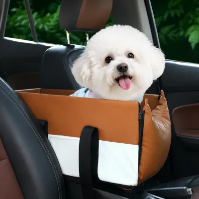 Small white dog sitting in a brown center console dog car seat between the front seats
