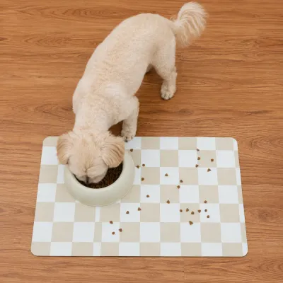 Waterproof Dog Feeding Mat for Messy Eaters Small dog eating from a food bowl on a beige checkerboard waterproof pet feeding mat.