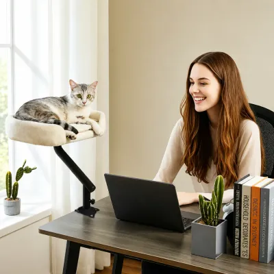 Desk Cat Bed for Home Office Workspace Grey and white cat relaxing in a desk-mounted plush bed beside a woman working on a laptop