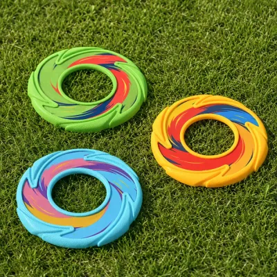 Green blue and yellow hollow TPR dog flying discs displayed on outdoor grass