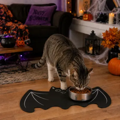 Cat Using Halloween Bat Feeding Mat Tabby cat eating from a bowl on a black bat shaped Halloween pet feeding mat