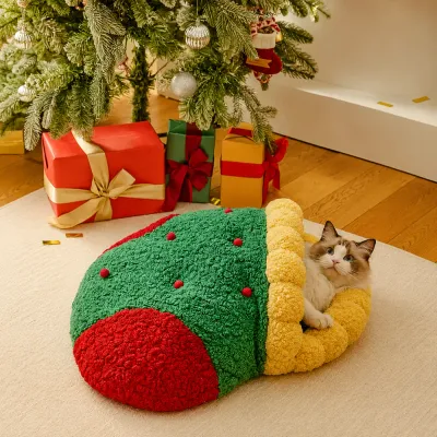 Christmas Stocking Cat Bed Holiday Lifestyle Scene Cat resting inside green red Christmas stocking bed beside Christmas tree and holiday gifts