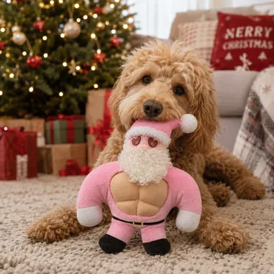 Dog Playing with Pink Santa Christmas Plush Toy Dog playing with a pink Santa squeaky plush dog toy beside a decorated Christmas tree