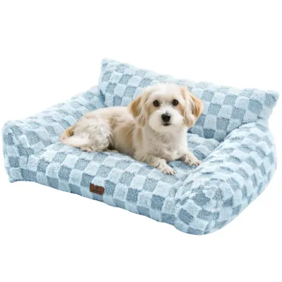 Small dog lying on a blue plush sofa dog bed with raised bolsters and soft cushioned surface