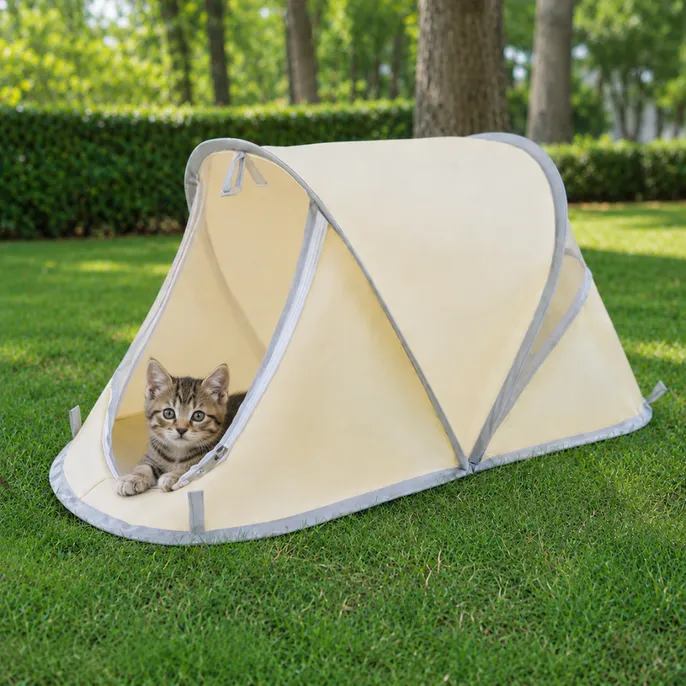 Kitten resting inside a cream portable pet tent on a grassy lawn