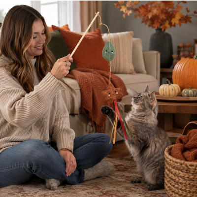 Autumn Cat Teaser Wand Interactive Play Woman playing with a cat using an autumn leaf cat teaser wand in a cozy fall living room