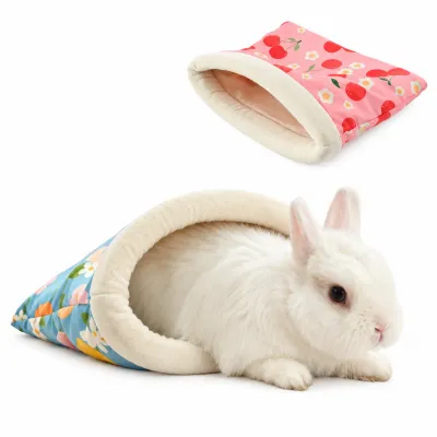 White rabbit resting inside a blue lemon patterned small pet sleeping bag with soft plush lining, alongside a pink cherry rabbit bed.